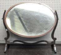 A Regency mahogany swing mirror of oval form, on scroll supports,