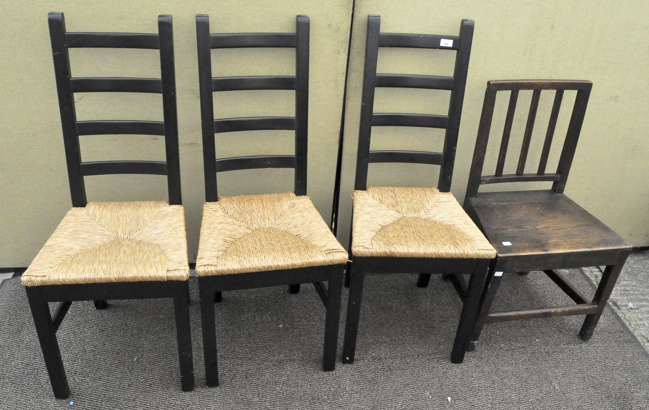 A set of three modern black painted ladder back chairs with rush seats, 104cm high,