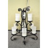 A large wrought iron nine branch chandelier, with frosted glass shades and s-scroll branches,