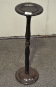 A metal ashtray raised on a turned stained wood stand,