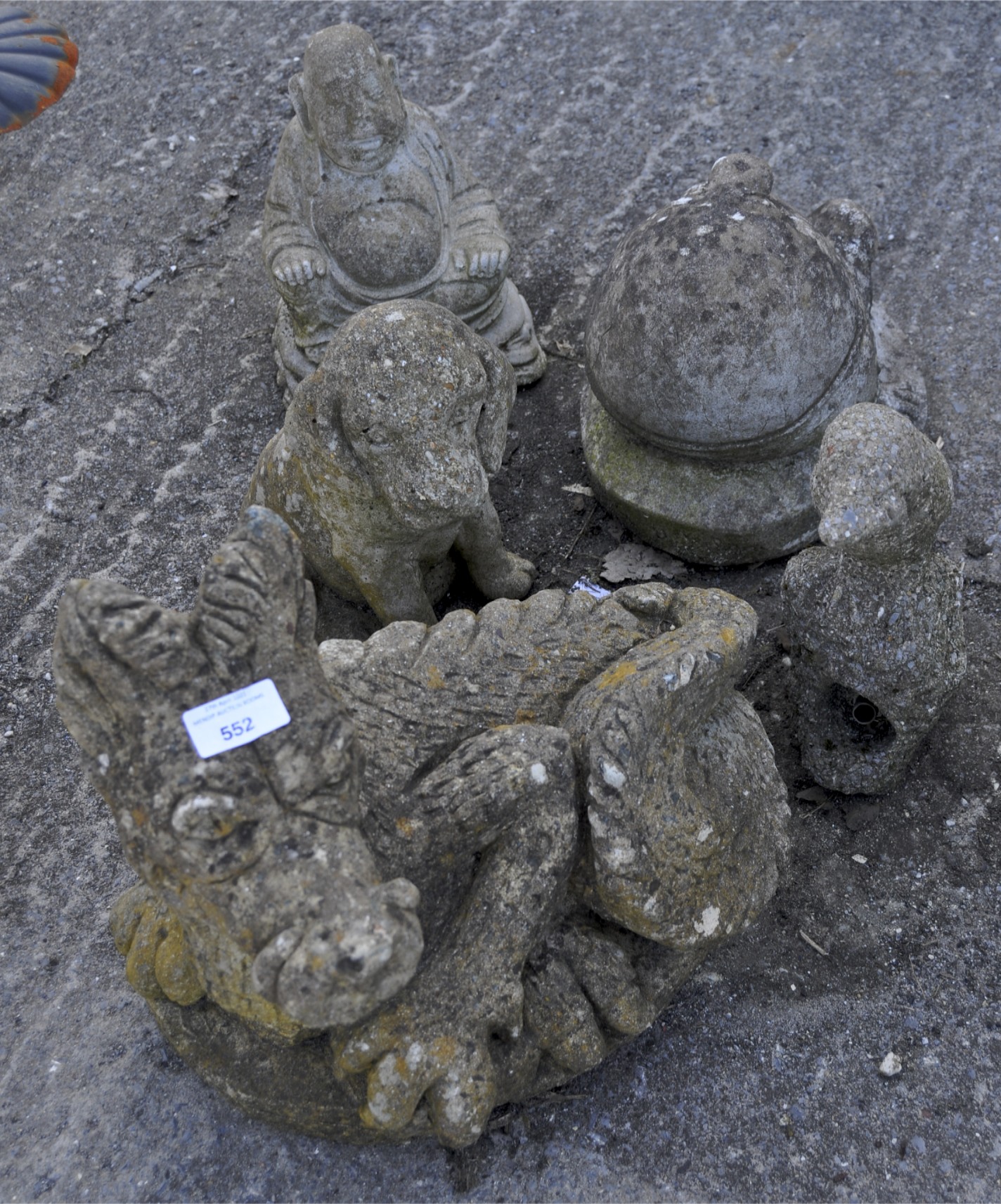 A collection of stone garden animals and sculpture, including Humpty Dumpty, a Buddha and a dragon,