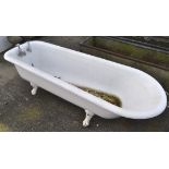 An early 20th century cast iron enamelled roll top bath tub, raised upon four claw and ball feet,