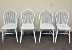 A set of four wheel back dining chairs, painted blue,