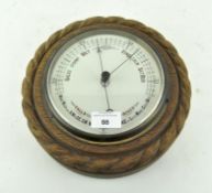 An oak cased wall barometer, of circular form with enamel dial,