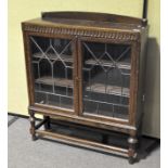 An oak glazed display cabinet, 20th century, with leaded astragals, enclosing two shelves,