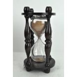 A vintage glass timer, with turned supports and wooden mount,