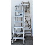 Three sets of ladders, comprising two metal and a wooden example,