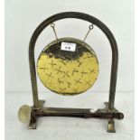 A 20th century brass gong on stand, adorned with cross like decoration,