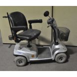 An Invacare mobility scooter and charger, fitted with baskets to front and back,