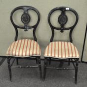 A pair of Victorian ebonised balloon back chairs, painted with bouquets of flowers,