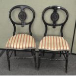 A pair of Victorian ebonised balloon back chairs, painted with bouquets of flowers,