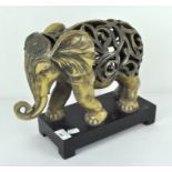 A stylised resin figure of an elephant, raised on wooden stand,