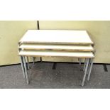 A set of three stacking school tables of rectangular form, each with four tubular metal legs,