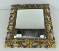 A small gilt wall mirror, with pierced and foliate frame and bevelled edge,