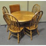 A contemporary oak extending circular dining table and four Windsor chairs,