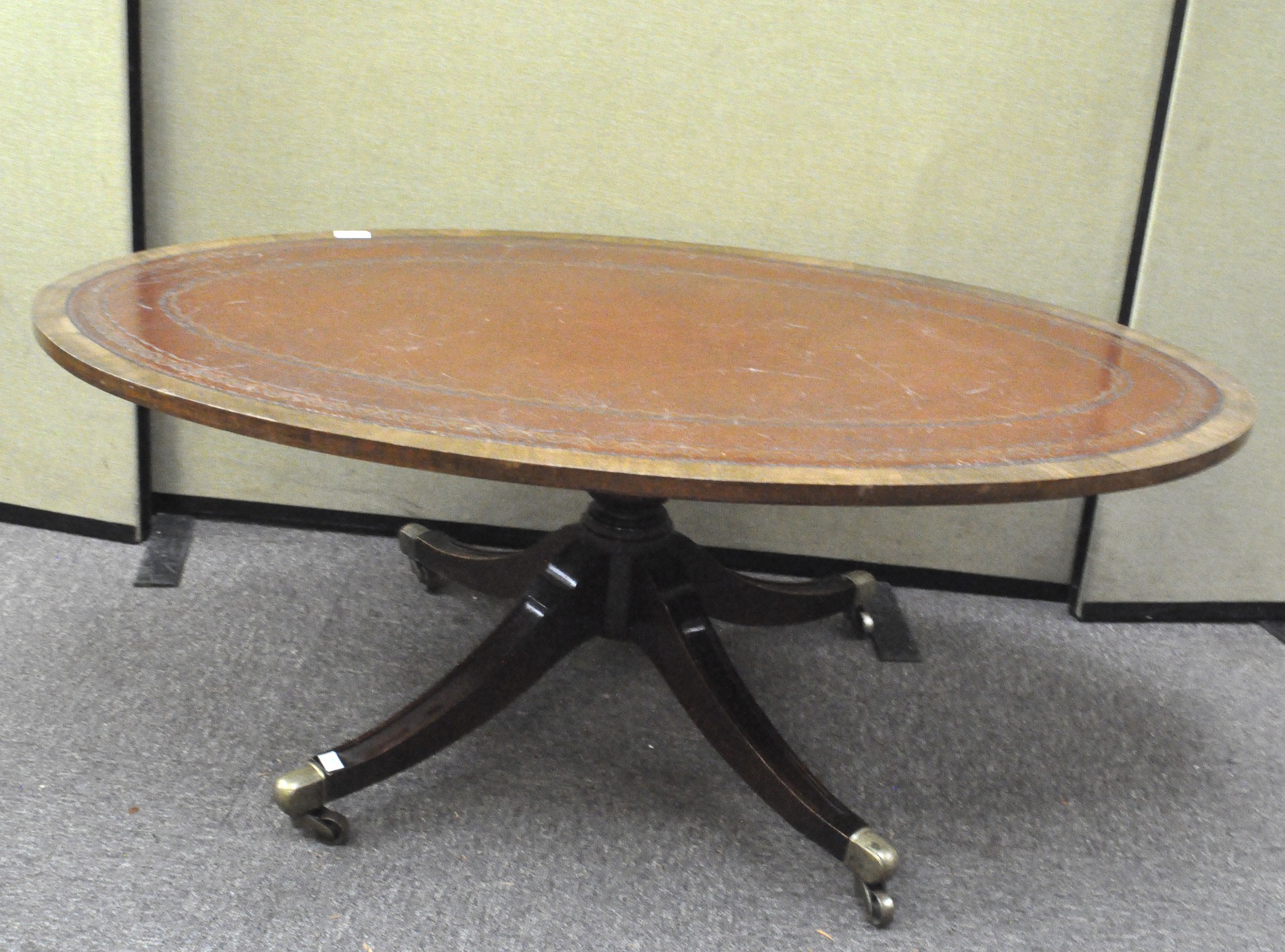 A Victorian oval top mahogany coffee table with leather top on brass castors