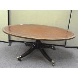 A Victorian oval top mahogany coffee table with leather top on brass castors