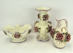 Three pieces of ornate ceramics, each adorned with floral decoration, comprising jug,