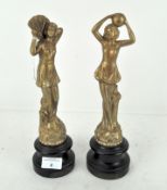 A pair of early 20th century figures of ladies, raised on turned wooden bases,