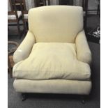 A cream upholstered armchair on casters