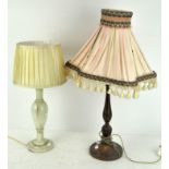 A turned mahogany table lamp together with a polished stone example, both with shades,