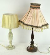 A turned mahogany table lamp together with a polished stone example, both with shades,