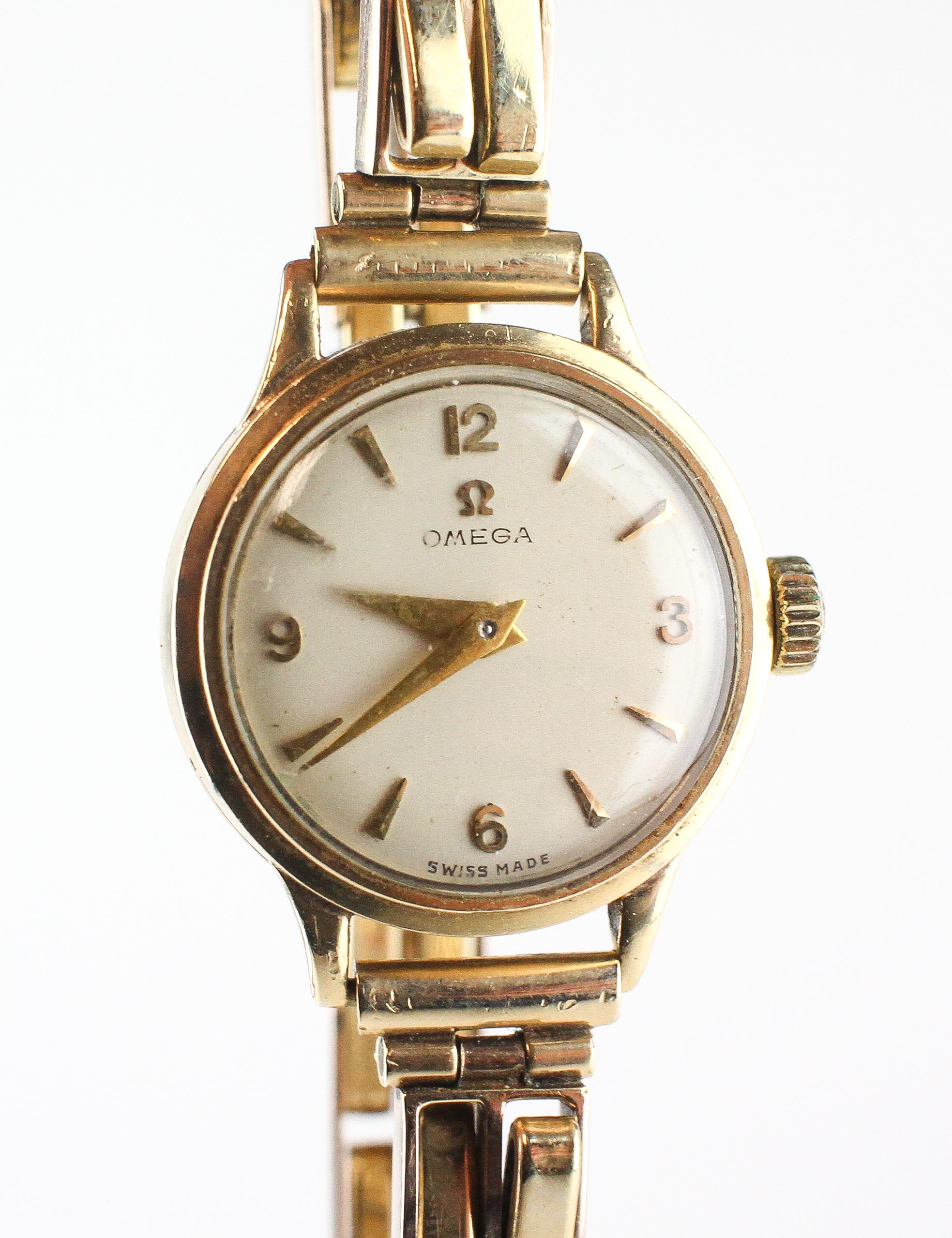 A yellow gold omega wristwatch. Circular champagne dial with mixed markings.