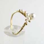 A yellow metal wishbone ring set with six cultured pearls ranging in size from 2.50mm to 5.50mm.