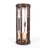 A large vintage hourglass timer, with brass mounted column supports,