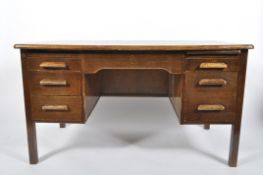 A mid century oak twin pedestal desk, with an arrangement of seven drawers around the kneehole,