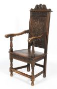 An oak Wainscot chair, with a foliate carved back, scrolling arms on baluster supports,
