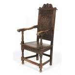 An oak Wainscot chair, with a foliate carved back, scrolling arms on baluster supports,