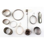 A collection of items to include: Three silver bangles; A rolled gold bangle;