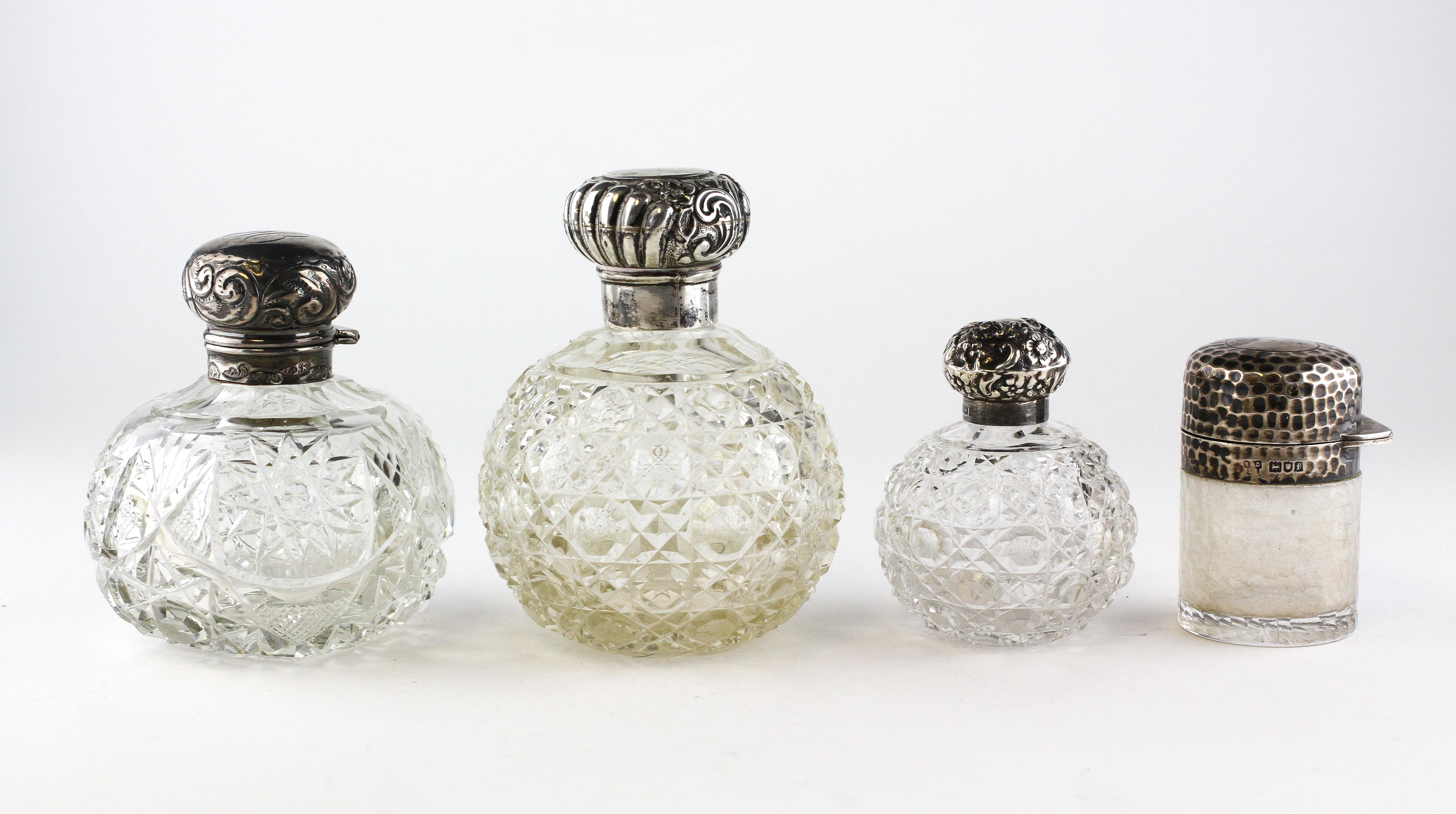 Three Edwardian silver topped cut-glass scent bottles and stoppers, each of globular form,