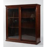 An Edwardian mahogany glazed bookcase with sliding double doors enclosing four adjustable shelves,