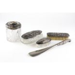 Five silver-mounted dressing table items, with embossed designs, including lidded powder bottles,
