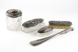 Five silver-mounted dressing table items, with embossed designs, including lidded powder bottles,