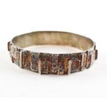 A white metal circular bangle of abstract design with textured finish.