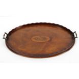 A Georgian mahogany tray, of oval form inlaid with a shell motif inside a wavy gallery,