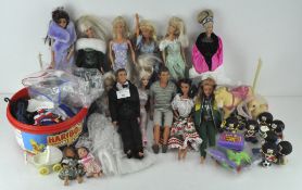 A collection of Barbie and Ken dolls together with some outfits.