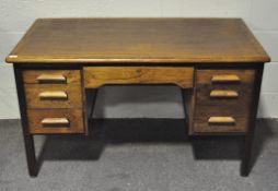 A large oak desk with single drawer to centre flanked to either side by three drawers,