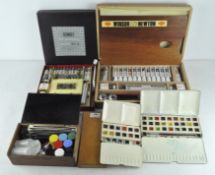 A collection of artist's equipment including various paints, brush boxes,