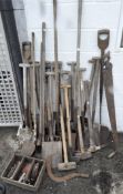 A large collection of gardening tools including shovels and saws