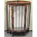 An Art Deco mahogany display cabinet of demi-lune form, raised upon four claw and ball feet,