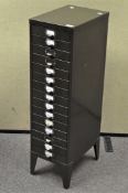 A tall thin metal filing cabinet, comprising fifteen drawers,