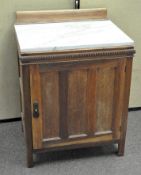 A marble topped oak side cabinet with one fitted door, opening to reveal two tiers,