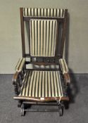 An early 20th century mahogany rocking chair, upholstered in striped green and cream fabric,