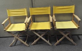 Three director's chairs with yellow fabric seats and back rests,