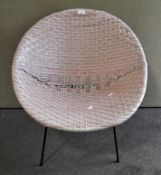 A retro satellite tub chair, of woven pink and white plastic, on metal feet,