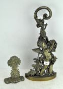 Two brass door stops, the largest with a Cherub amongst vines,